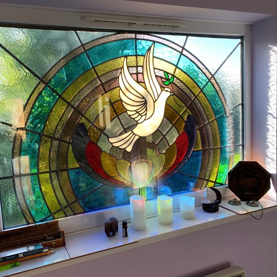 Stained glass dove window in Katy's yoga space with candles below
